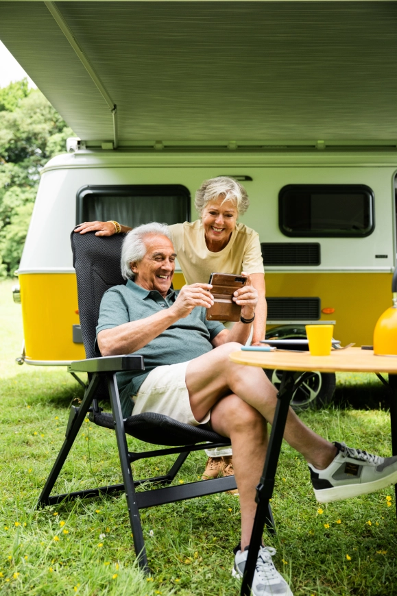 Stel geniet zorgeloos bij een gele Eriba caravan na het kopen van een tweedehands caravan